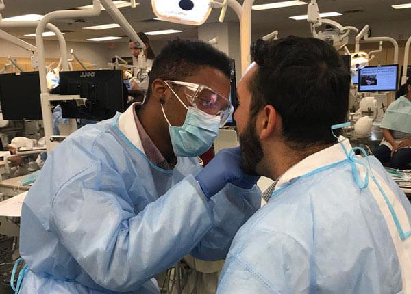 Health students in scrubs performing dental exam